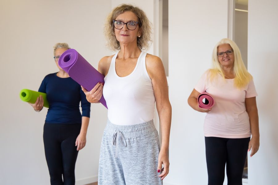 Mulheres com tapetes de ioga antes de uma aula em grupo