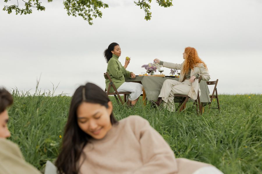 Amigas reunidas em volta de uma mesa de piquenique ao ar livre
